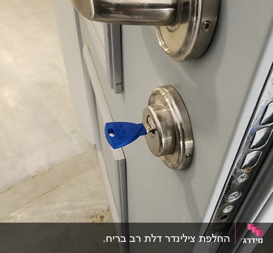 צילינדר מנעול שהוחלף בדלת כניסה עם מפתח כחול מוכנס בתוכו